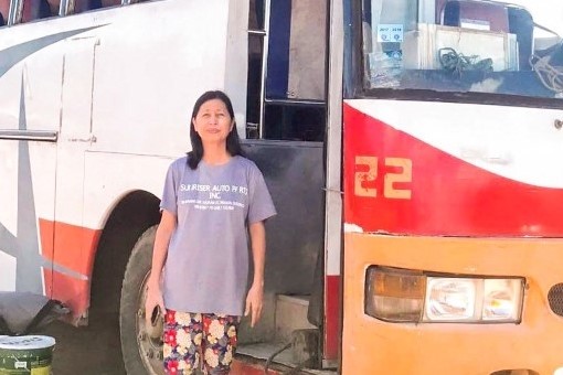 Nanay Leah standing in front of one of her buses