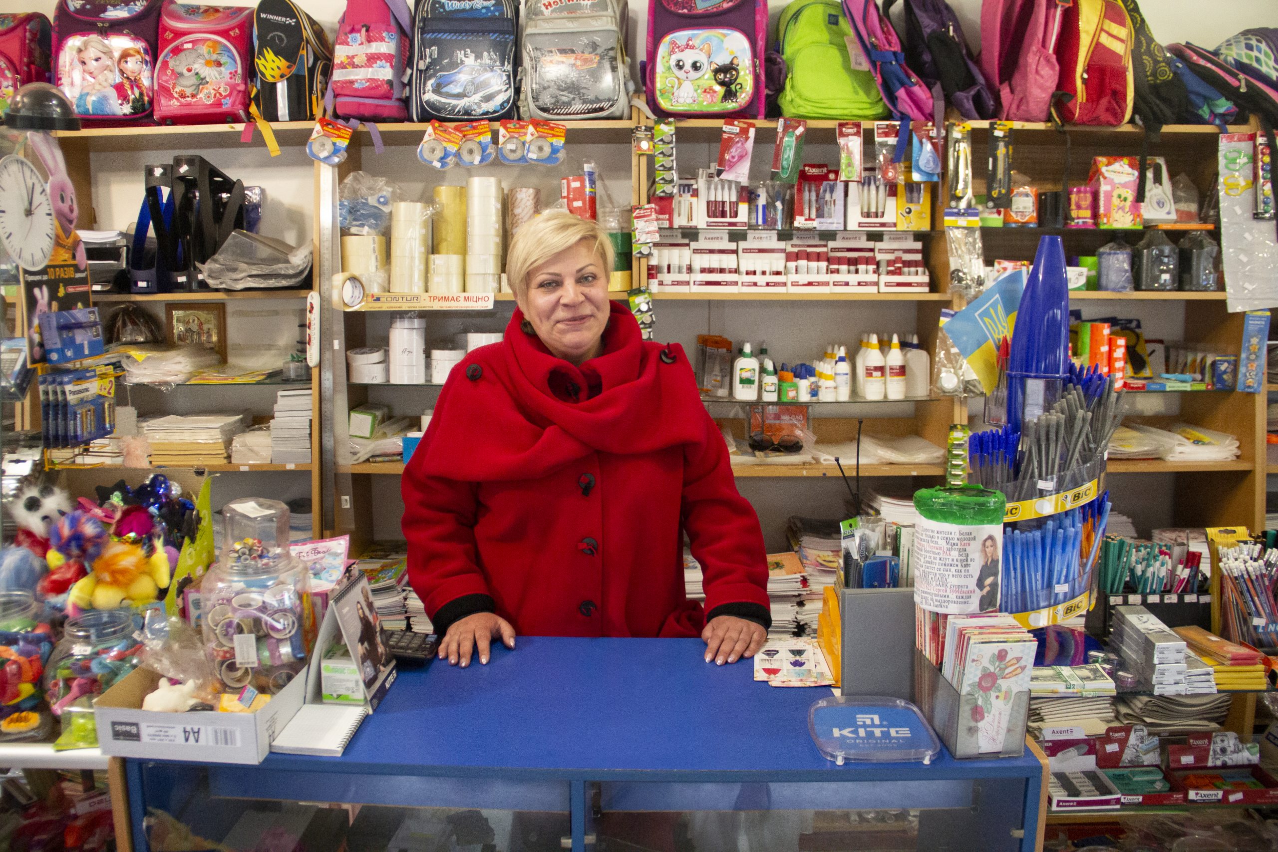 A woman smiles behind the counter of her shop.